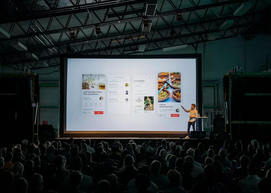 Spreker voor een groot publiek met een presentatie op het scherm